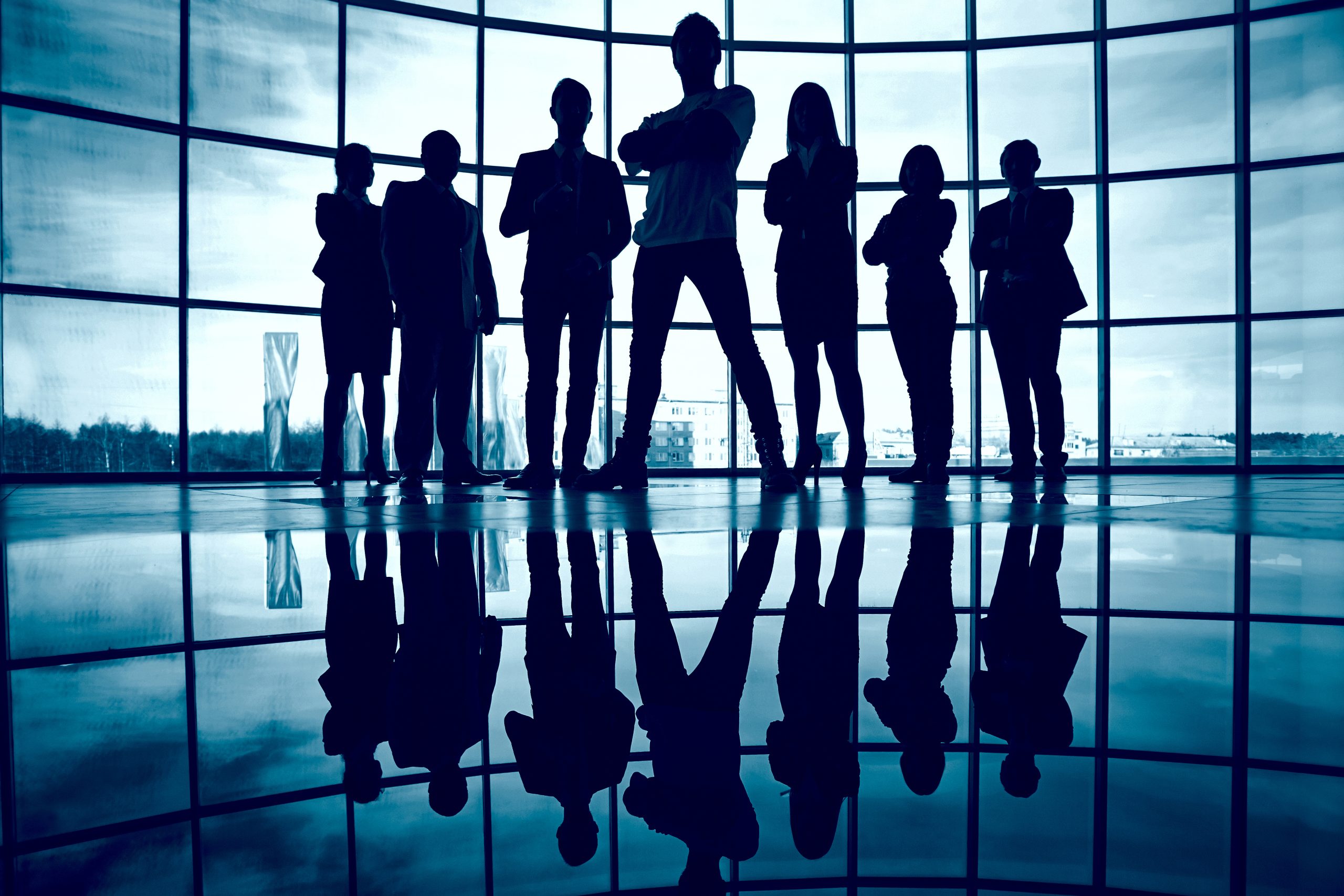 Business team standing against window with leader in front